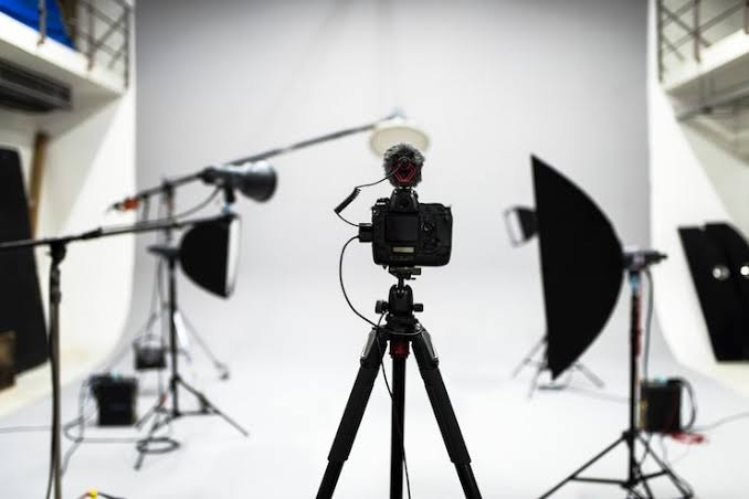 Professional film studio with cinema camera on tripod and lighting equipment
